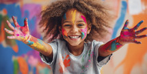 Smiling young girl with vibrant paint splatters on her face and hands, showcasing creative joy.