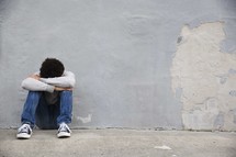 a depressed teen boy sitting alone.