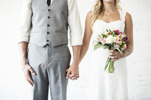 portrait of a bride and groom holding hands together. 