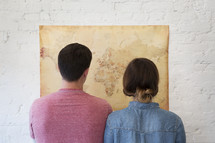 a couple looking at a world map 