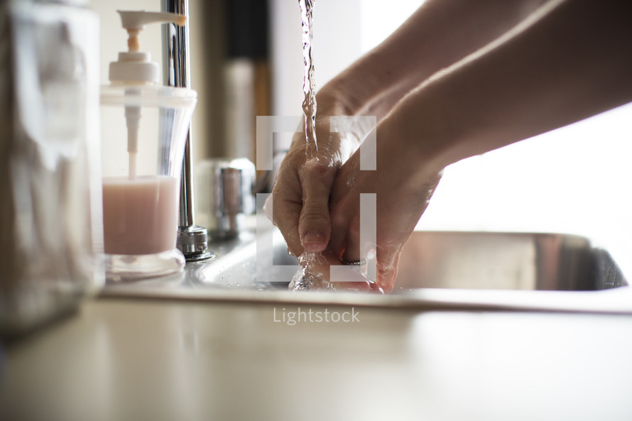 a  woman washing her hands in a sink.