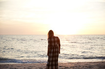 a woman looking out at the ocean at sunset 