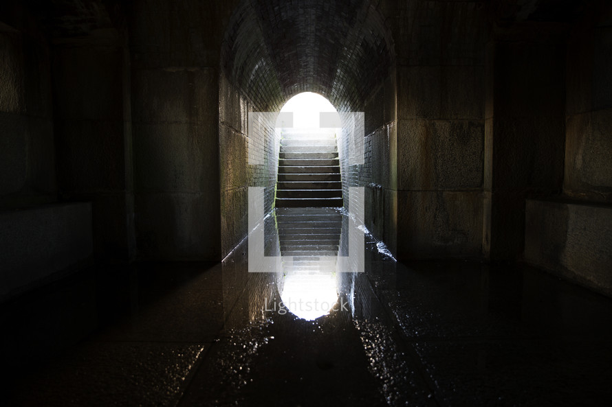 reflection in water at the bottom of a dark tunnel.