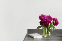 fuchsia flowers in a vase and a Bible on a wood table 