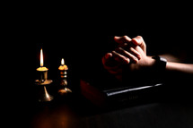 Bible and candlelight with praying hands