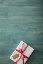 wrapped gift on a wood floor and a Christmas gift list 