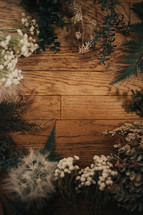 frame of plants, flowers, and grasses on a wood background 