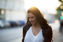 a young woman walking down a sidewalk at sunset 