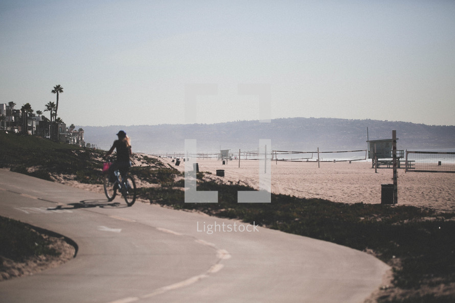 a man riding a bike on a curvy road near a beach 