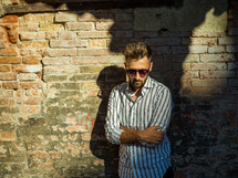 a man posing in front of a brick wall 
