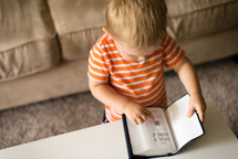 a toddler boy reading a Bible 