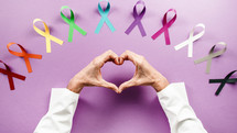 world cancer awareness day ribbons and hand heart shape of a doctor