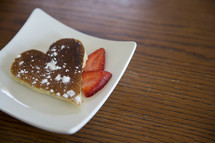 heart shaped pancake and strawberries on a plate 