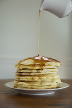 pouring sugar on a stack of pancakes 