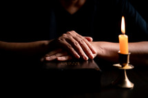 Bible and candlelight with praying hands