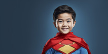 Cheerful young Asian boy in colorful superhero costume with a cape, posing confidently against a dark blue background.