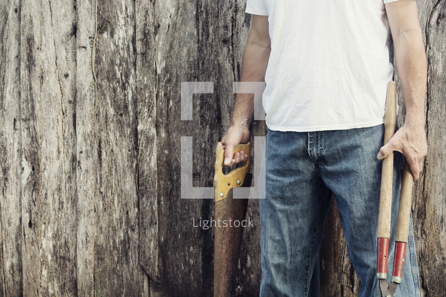 man holding saw and clippers 