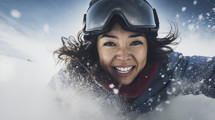Dynamic close-up of a joyful woman snowboarding on a sunny day.