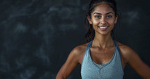 Fit young smiling woman in athletic wear against a dark textured background.