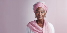 Graceful mature woman in pink turban and scarf with a serene expression.