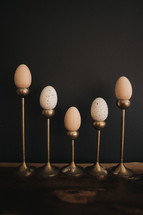 wooden eggs on candlesticks against a black background with copy space 