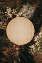 frame of plants, grasses, and flowers on a wood background 