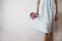 A girl in a white dress holding a bouquet of flowers.