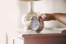 woman's hand reaching for an alarm clock in her room. 
