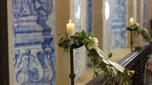 Church decoration with candle, flowers and blue tiles.