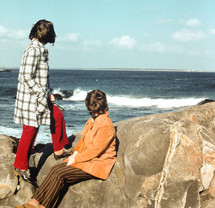 vintage image of people sitting on rocks looking out at the ocean 