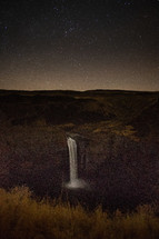 stars in the night sky above a waterfall 