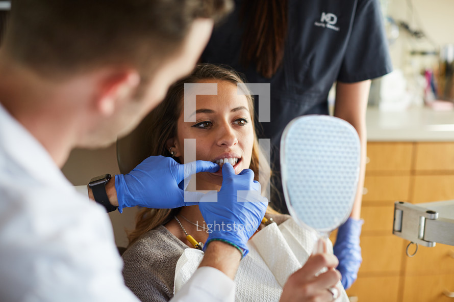 a dentist and dental hygienist with their patient in an exam room 