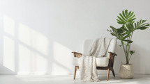 Serene and stylish corner with a white armchair, soft blanket, and lush monstera plant.