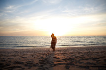 a woman standing on a beach at sunset 