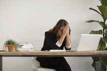 a businesswoman sitting behind a desk praying 