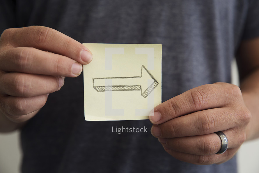 man holding a post-it note with an arrow 