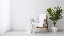Minimalist design with a sleek white armchair, soft throw blanket, and vibrant potted plant.