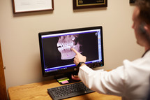 a dentist looking at X-rays on a computer screen 