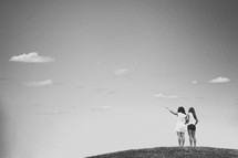 Girlfriends standing on a hill.