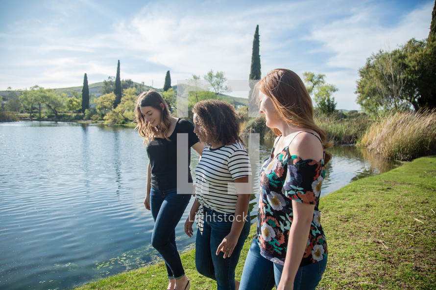 women walking and talking along a lake shore 