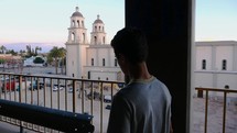 A young man walking downtown, looking at a church