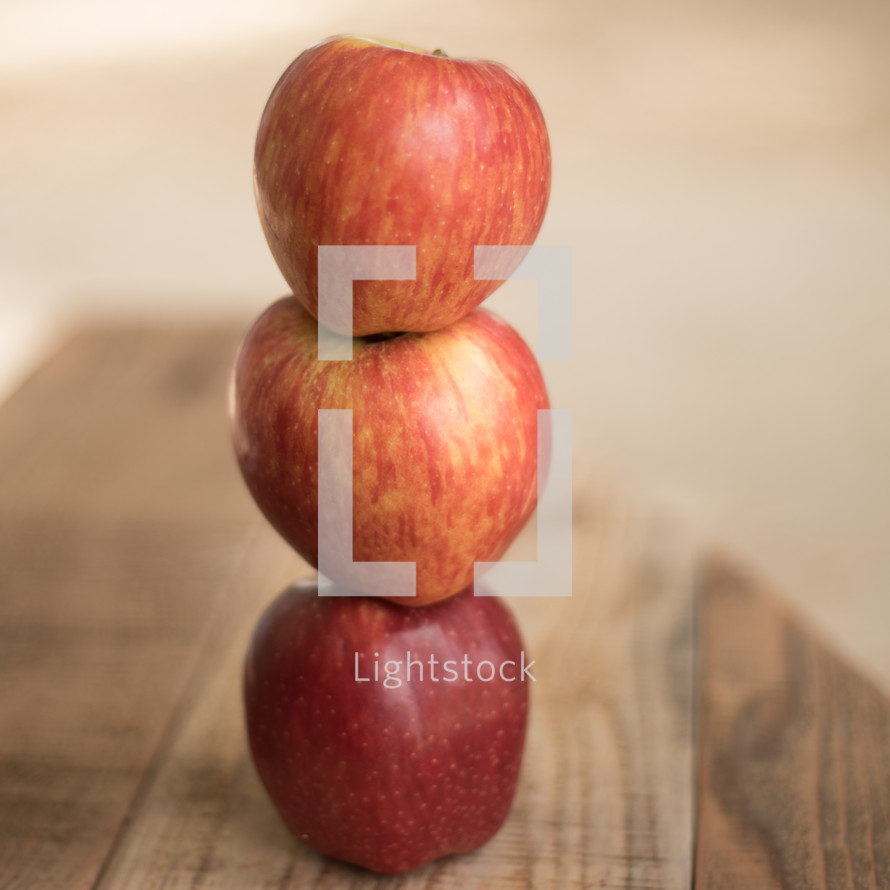 stacked red apples on wood countertop 