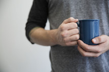 A man holding a blue coffee cup.