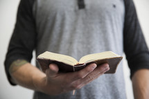 A man holding an open book in one hand.