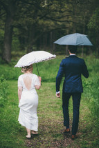 a bride and groom carrying umbrellas in the rain 