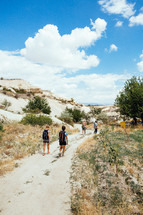 people hiking along a sand trail at a shore 