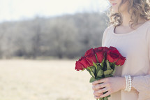 woman holding a bouquet of red roses outdoors 