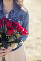 girl holding a bouquet of red roses.