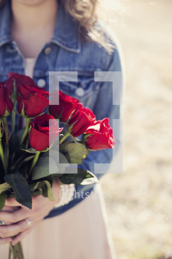 girl holding a bouquet of red roses.
