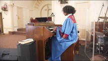 Women playing the organ wearing a choir robe